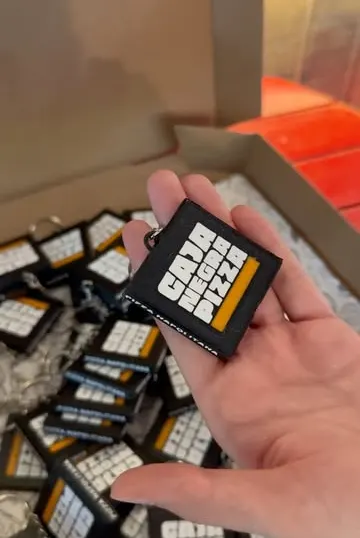 Una mano con varias cajitas negras con el logo de Caja Negra Pizza