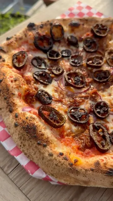 Una pizza napolitana de Caja Negra, entera, con la orilla inflada y tostada