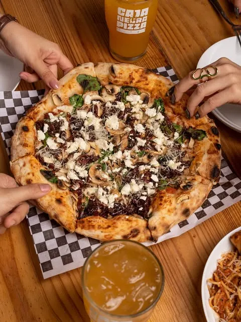 Pizza con queso desmoronado sobre el papel a cuadros